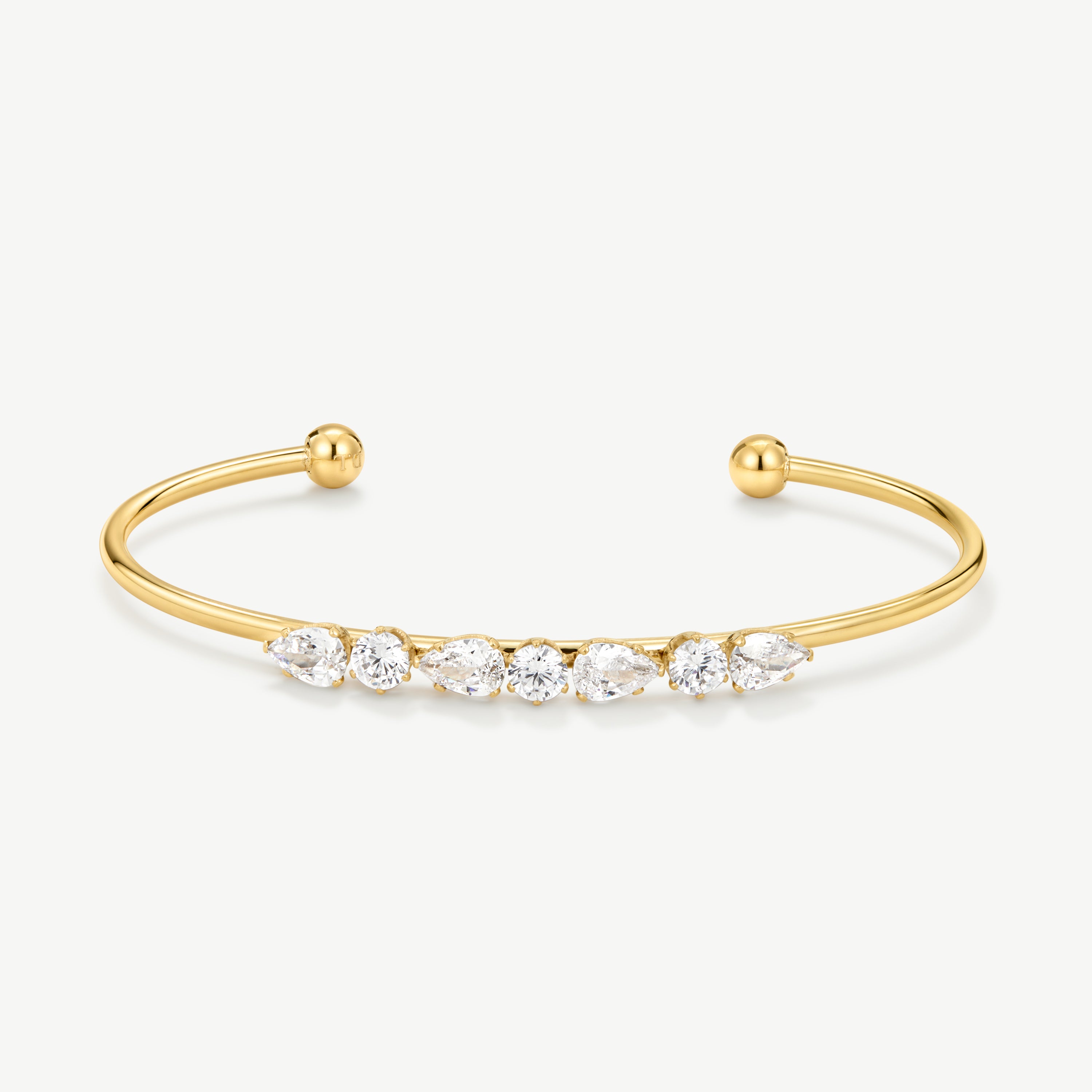 A gold open cuff bracelet featuring a row of clear marquise and round-cut gemstones across the front, displayed on a clean off-white background.