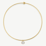 A delicate gold wire circle necklace with a small bezel-set clear gemstone pendant, shown on a clean off-white background.