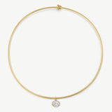 A delicate gold wire circle necklace with a small bezel-set clear gemstone pendant, shown on a clean off-white background.
