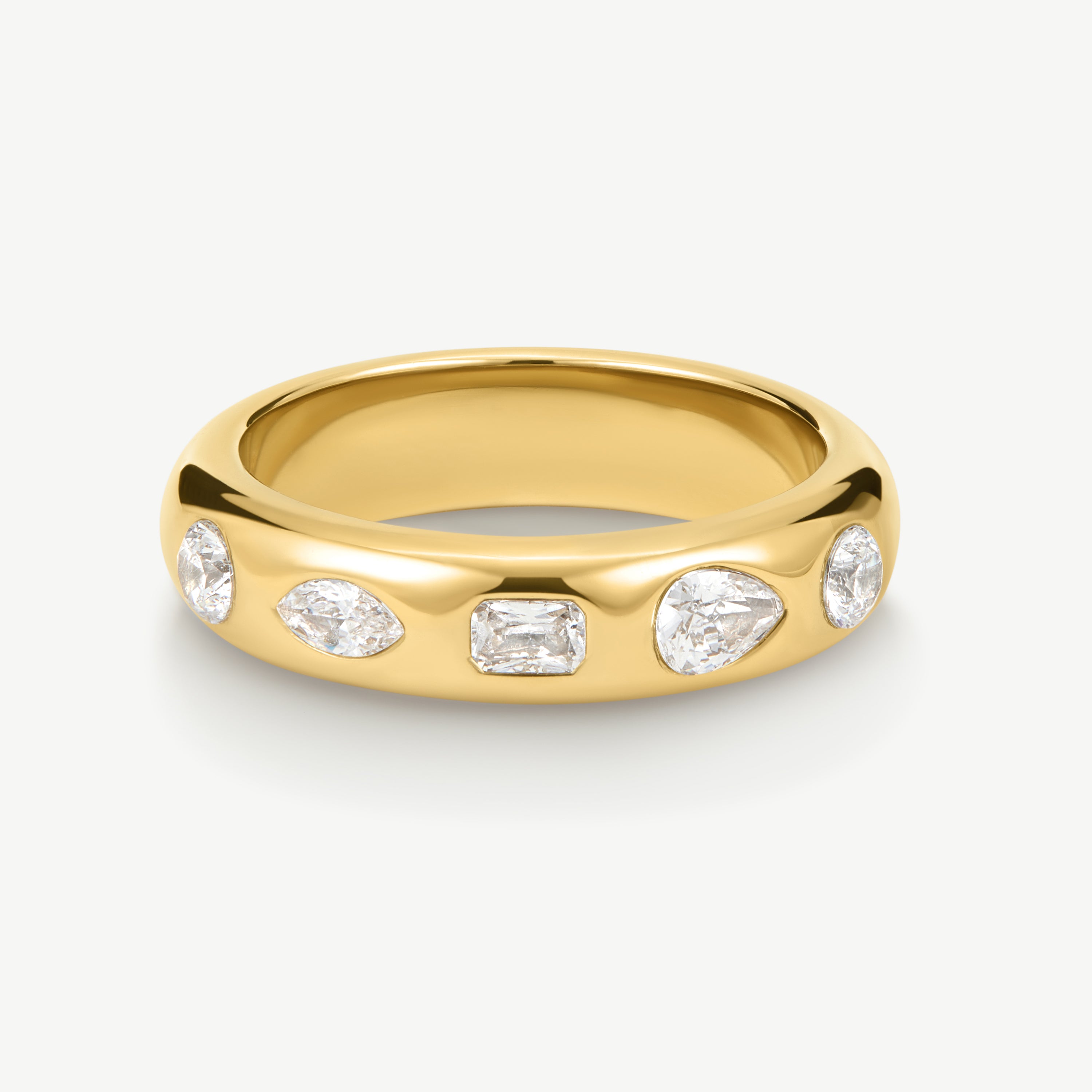A polished yellow gold band ring featuring five clear gemstones in marquise, rectangular, and round shapes, set against a clean off-white background.